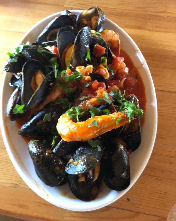 a bowl of food with mussels on a table at Gregory's Village in Platy