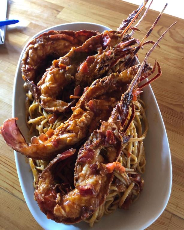 a plate of food with shrimp and pasta on a table at Gregory's Village in Platy