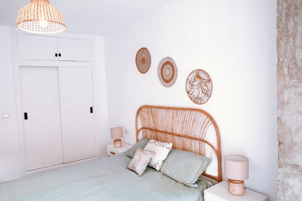 a white bedroom with a bed and two pillows at Mikasika - Duplex Apartment with seasonal swimming pool & walking distance from the beach in Cala del Moral