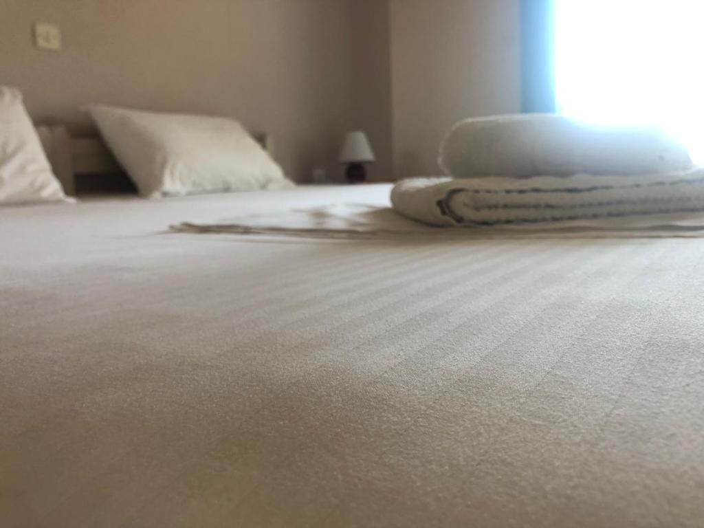 a white bed with white sheets and a window at Gregory's Village in Platy
