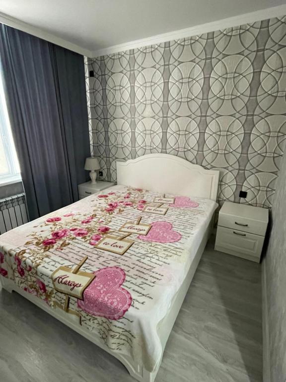 ein Schlafzimmer mit einem Bett mit rosa Kissen darauf in der Unterkunft Апартаменты у Натальи in Aqtau