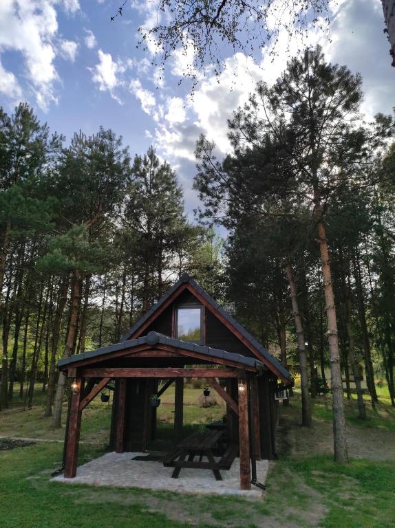 a gazebo with a bench in a forest at Dom Nad Stawem Krawno in Piecki
