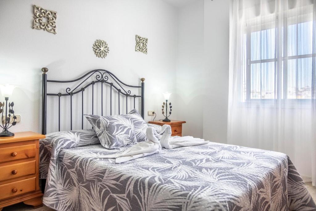 1 dormitorio con cama con colcha gris y blanca en La Ensenada, apartamento junto al mar, en Barbate