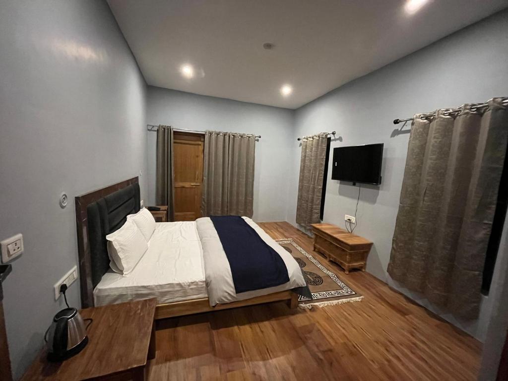 1 dormitorio con 1 cama y TV de pantalla plana en Honey Bee, en Leh