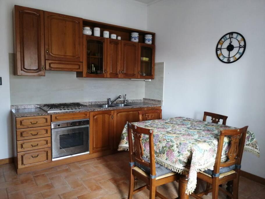 - une cuisine avec des placards en bois, une table et un évier dans l'établissement Appartamento Il Cedro, à Rosia
