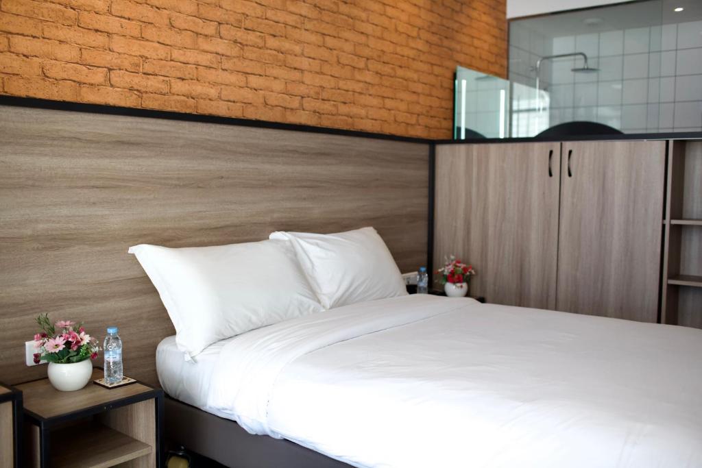 a bedroom with a white bed and a brick wall at ONOMO Hotel Tanger Med in Tangier