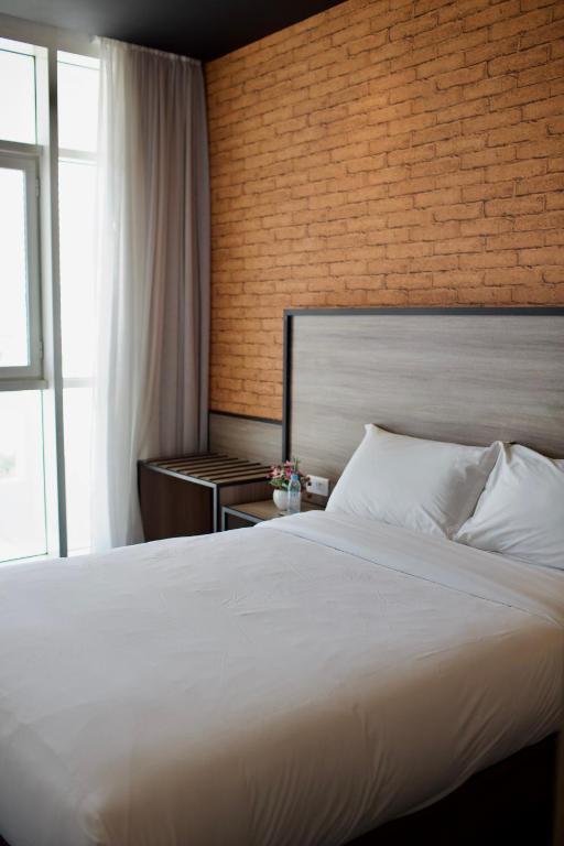 a bedroom with a large bed and a brick wall at ONOMO Hotel Tanger Med in Tangier