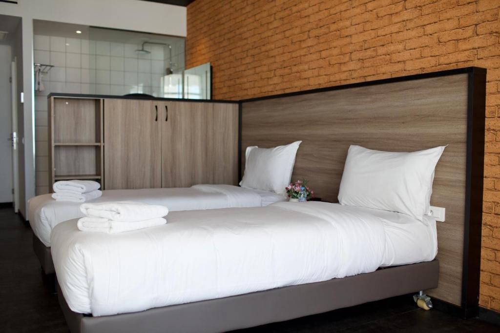 two beds in a room with white sheets and towels at ONOMO Hotel Tanger Med in Tangier