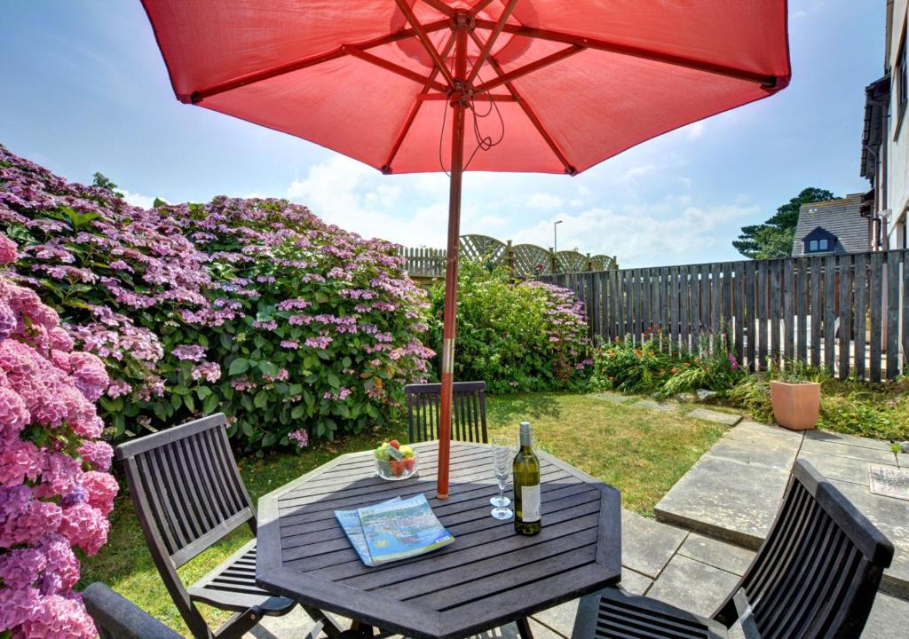 a table with a red umbrella and a bottle of wine at Mena-Gwins in Padstow