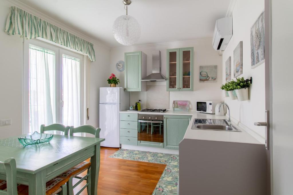 a kitchen with green cabinets and a white refrigerator at Attico Centralissimo Vista Mare in Torvaianica