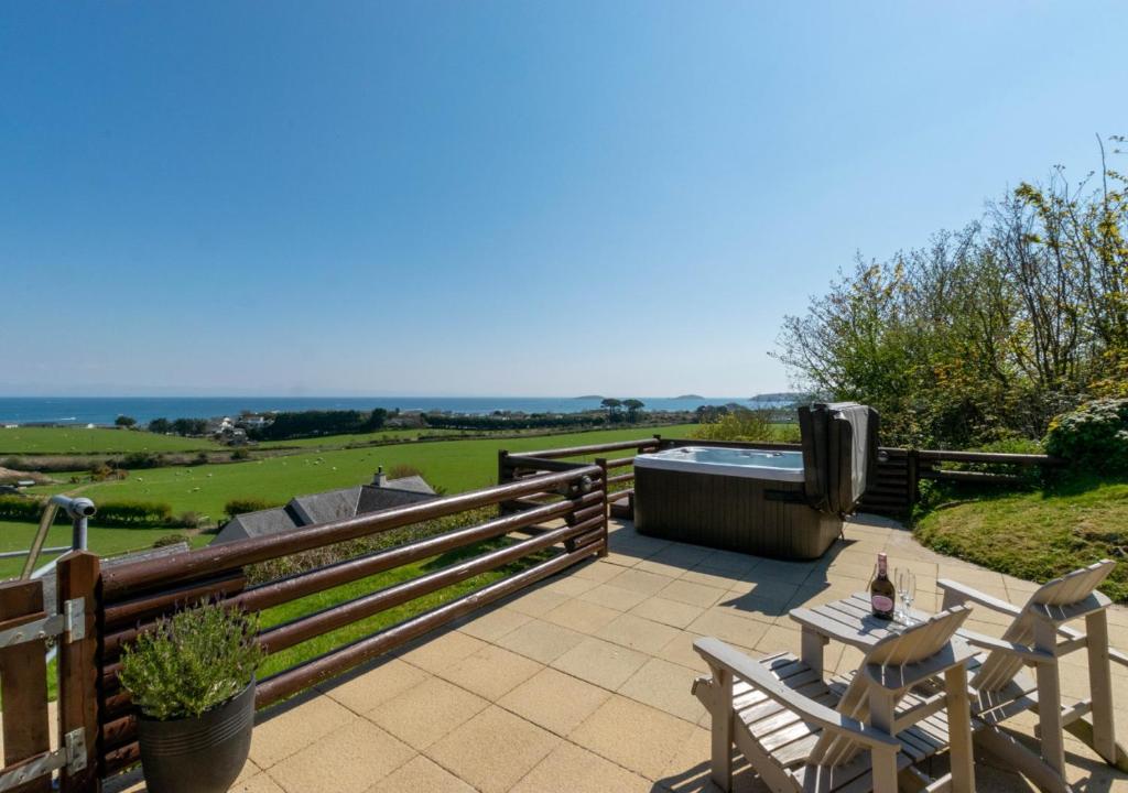 a patio with a hot tub and a table and chairs at Gorwel in Abersoch