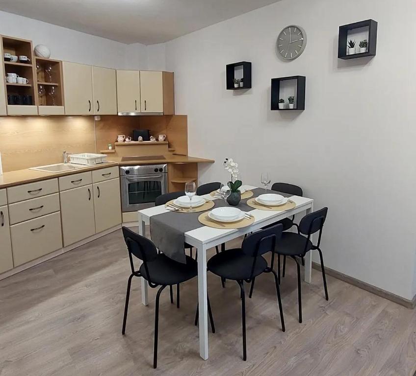 eine Küche mit einem weißen Tisch und schwarzen Stühlen in der Unterkunft Sunshine Resort Apartment in Hajdúszoboszló