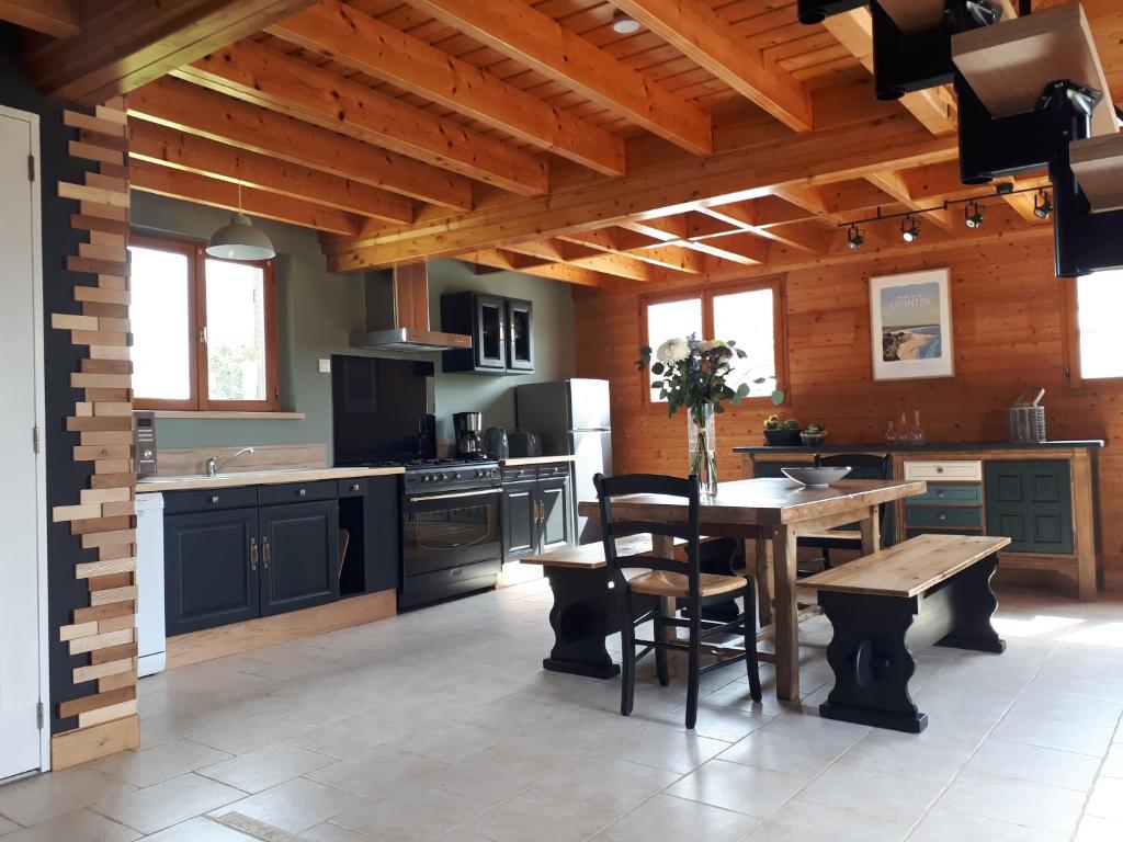 eine Küche mit einem Tisch und einer Holzdecke in der Unterkunft LE CHALET in Saint-Pierre-dʼArthéglise