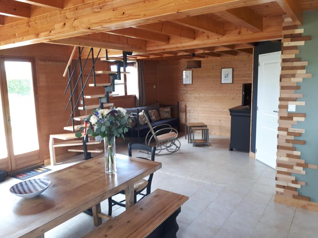 ein Wohnzimmer mit einem Tisch und einer Treppe in der Unterkunft LE CHALET in Saint-Pierre-dʼArthéglise