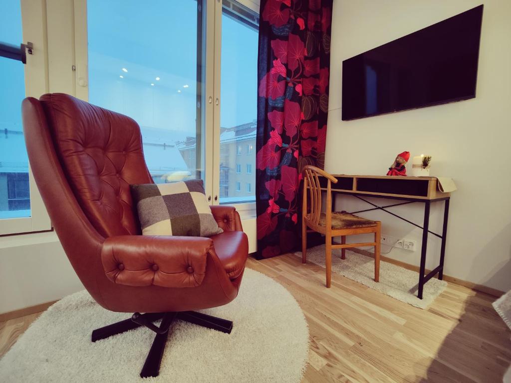 a living room with a brown leather chair and a desk at Ydinkeskustassa, uusi yksiö+ autohallipaikka in Tampere