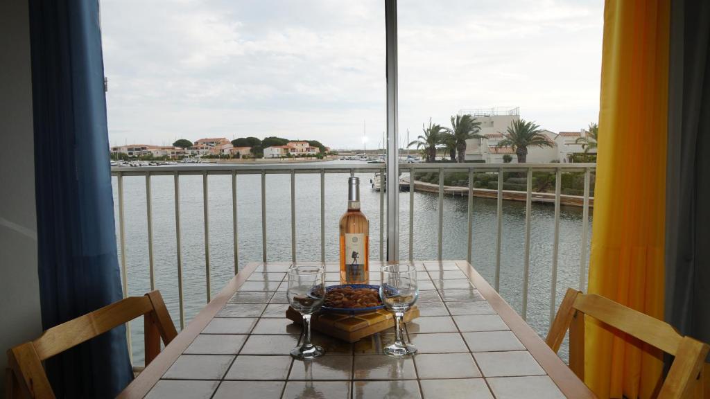 een tafel met een fles wijn op een balkon bij Ancre et Mouettes in Saint-Cyprien