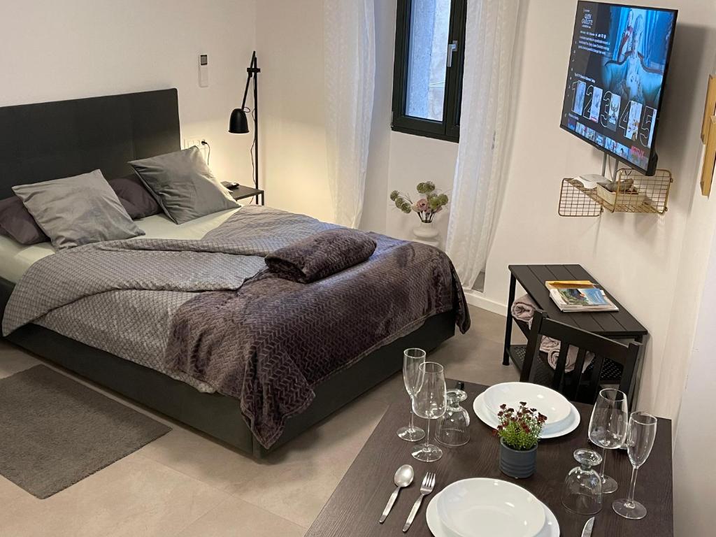 1 dormitorio con 1 cama y 1 mesa con copas de vino en Apartments Piranom, en Piran