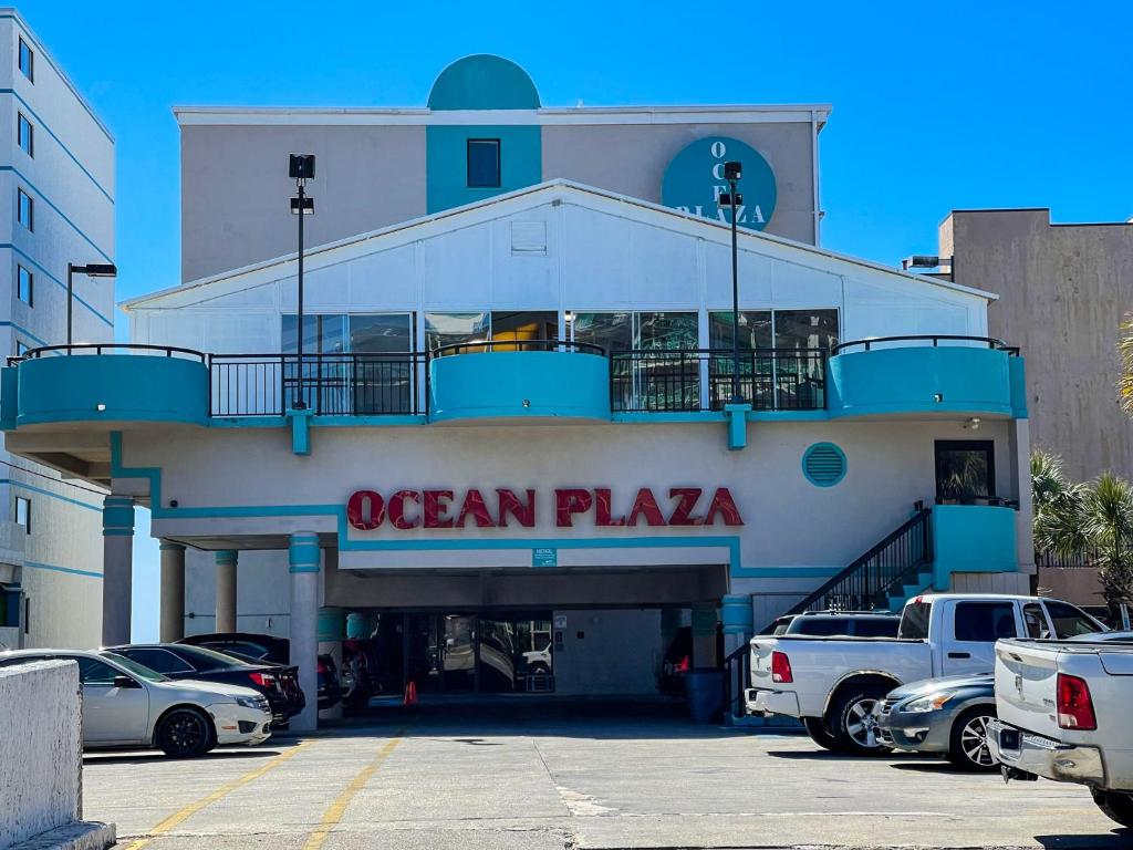 a building with an ocean plaza with cars parked in a parking lot at Ocean Plaza Motel in Myrtle Beach