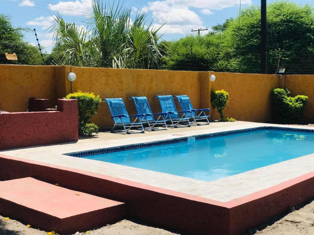 a swimming pool with blue chairs next to a fence at GardenView Holiday Home in Maun