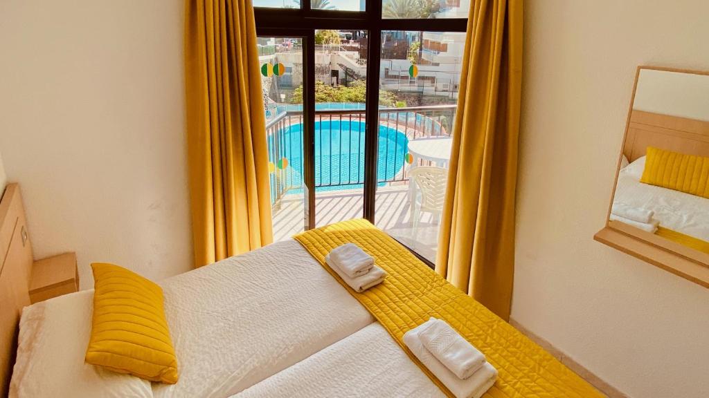 a bedroom with a bed and a view of a pool at Sunny apartment near the beach in Playa del Ingles