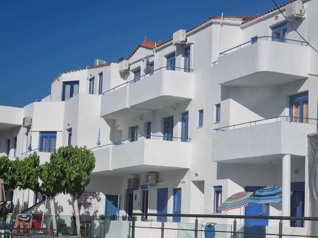 Um edifício branco com uma bandeira americana à frente. em Leonidas Studios & Apartments em Georgioupolis