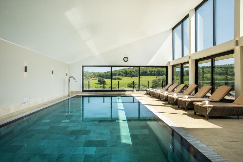a pool in a house with chairs and windows at Klein Zwitserland in Slenaken