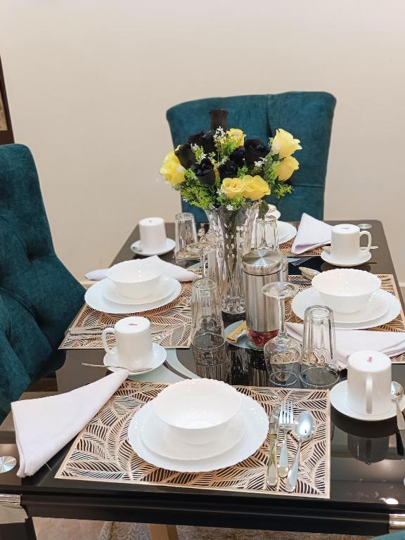 a table with white plates and a vase of flowers at Luxurious 2bedroom furnished apartment in Nairobi
