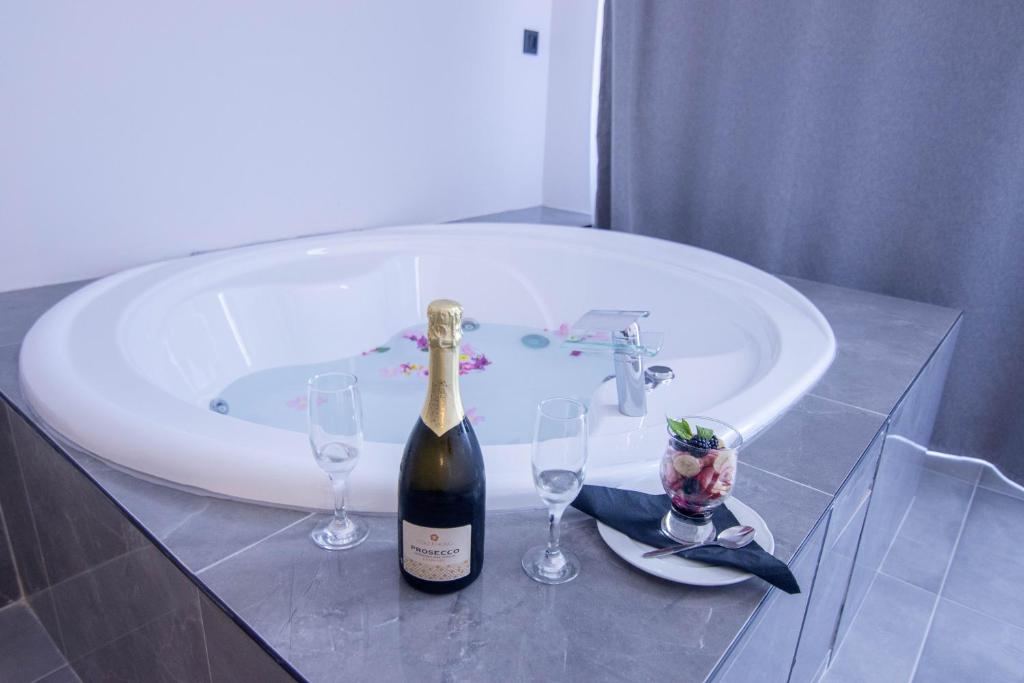 a bottle of champagne and two wine glasses in a bath tub at FRESH HOTEL FALIRAKI in Faliraki