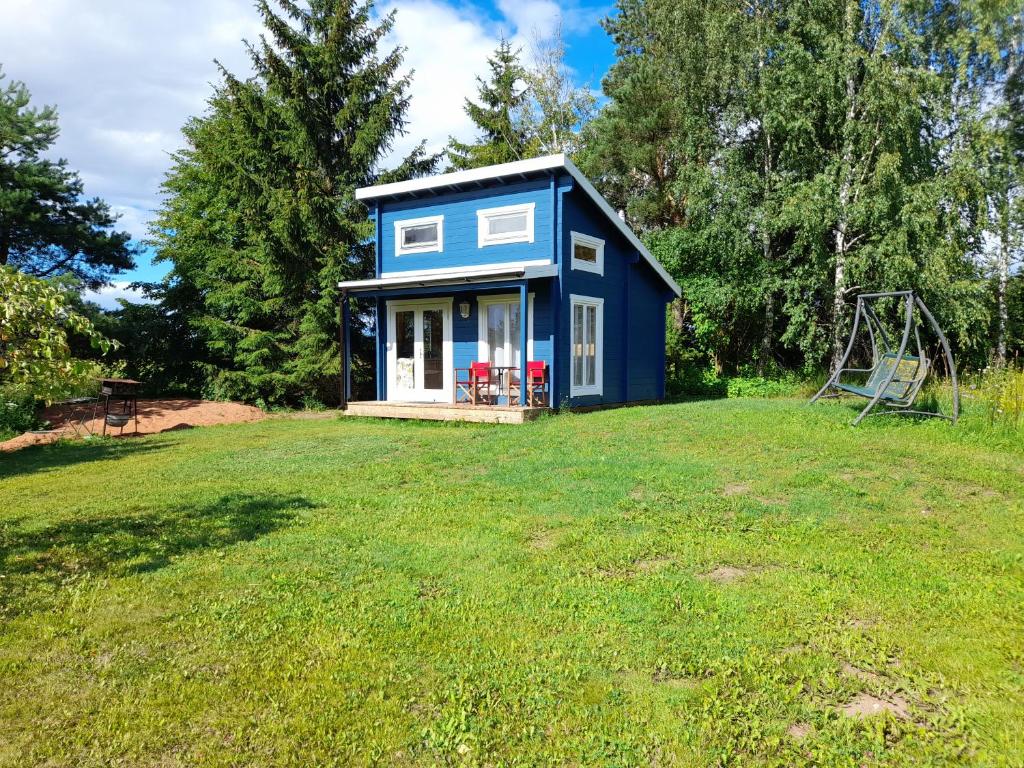 une petite maison bleue dans une cour avec une balançoire dans l'établissement Koobamäe saunamaja, à Kulli