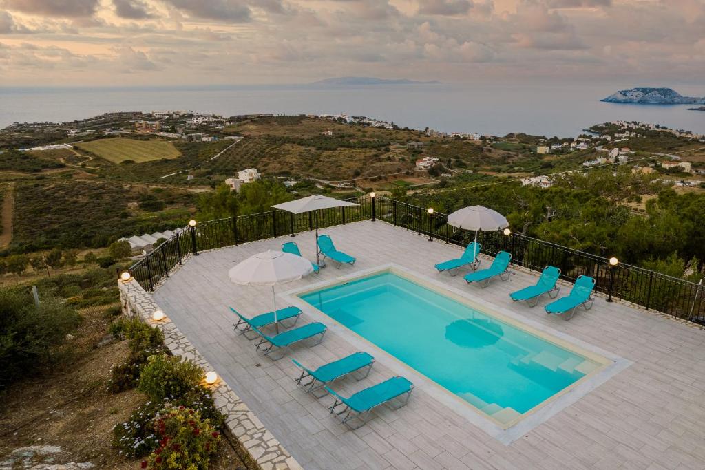 uma vista superior para uma piscina com cadeiras e guarda-sóis em Villa Aura Pine em Agia Pelagia