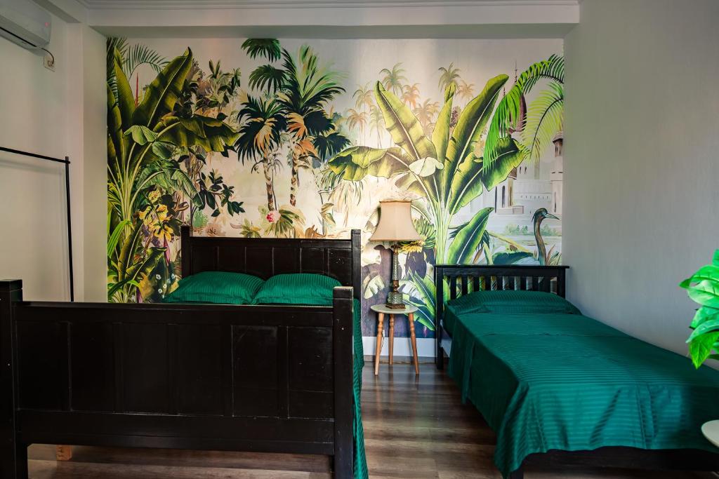 een slaapkamer met 2 bedden en een muurschildering van planten bij The Tropical House Tirana in Tirana