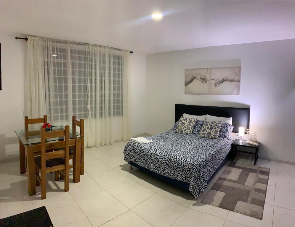 um quarto com uma cama, uma mesa e uma secretária em El Rincón de Granada Hotel em Cali