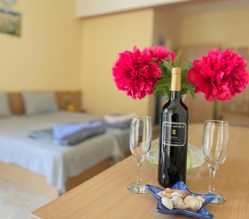 eine Flasche Wein und zwei Gläser auf dem Tisch mit Blumen in der Unterkunft Family Hotel Morska Zvezda in Baltschik