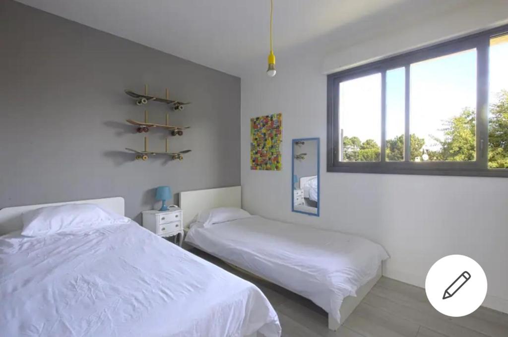 モリエ・エ・マーにあるVilla Côte d'Argentの白いベッドルーム(ベッド2台、窓付)