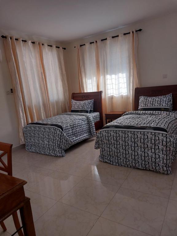 1 dormitorio con 2 camas y ventana en Julie's Marvelous home, en Dar es Salaam