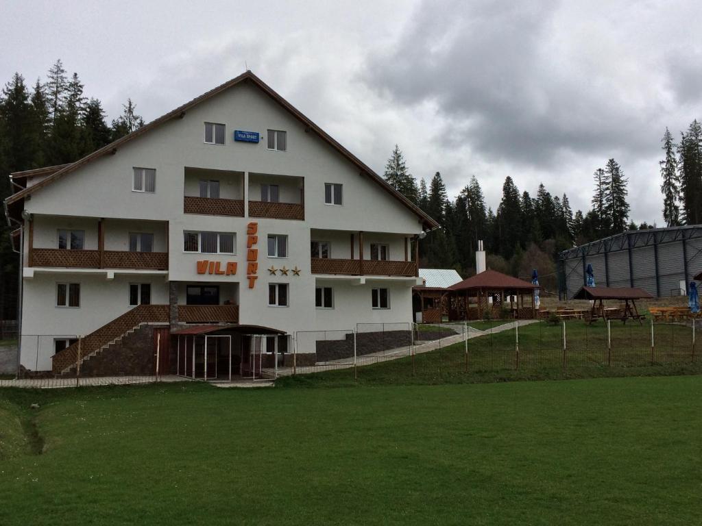 un gran edificio blanco frente a un campo en Vila Sport Borsec, en Borsec