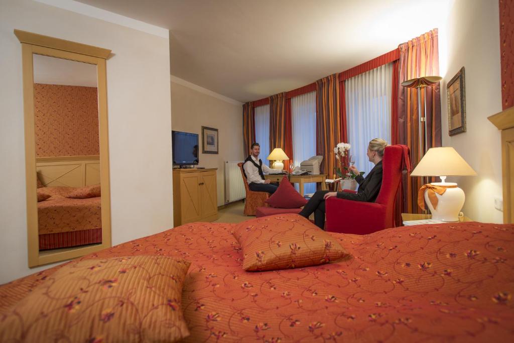 ein Hotelzimmer mit einem Bett und zwei Stühlen sitzenden Personen in der Unterkunft Hotel Residenz in Bocholt