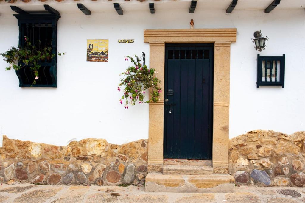 una casa blanca con una puerta negra y dos ventanas en Casa Clásica con Chimenea!, en Villa de Leyva