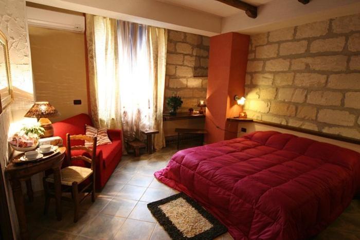 a bedroom with a large red bed and a table at B&B Alfrantoio Valderice in Valderice