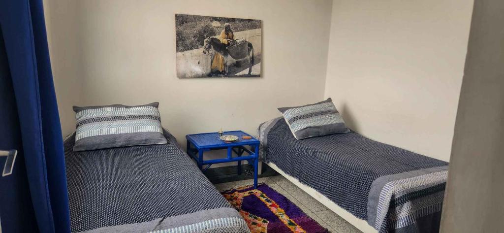 a room with two beds and a picture on the wall at Hotel-Restaurant Le Kaouki in Sidi Kaouki