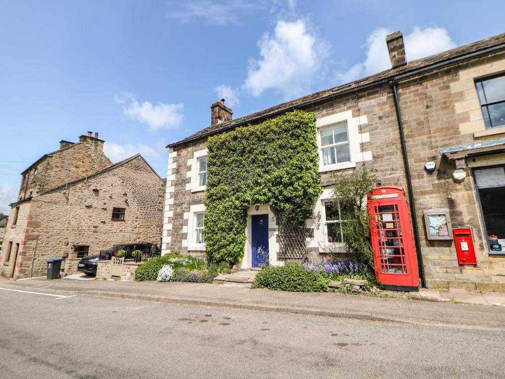 a red phone booth in front of a brick building at Millward House in Longnor