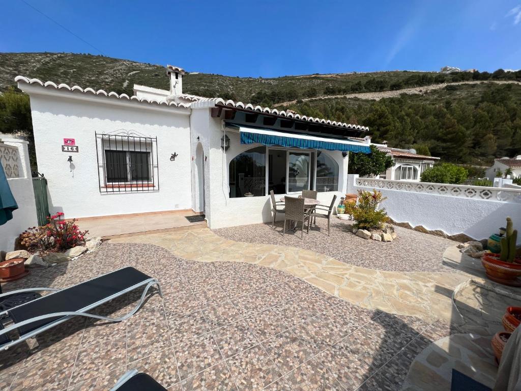 Casa blanca con patio con mesa y sillas en Luces Del Mar Beautiful bungalow with seaview near to Moraira en Benitachell