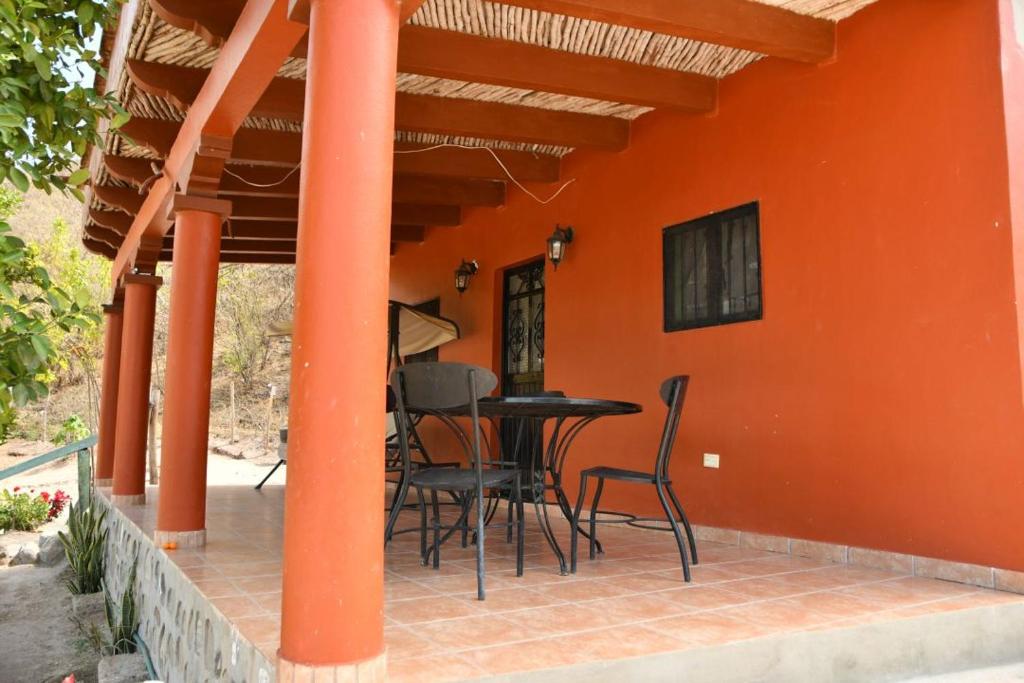 a patio with a table and chairs on an orange wall at La casita in Álamos