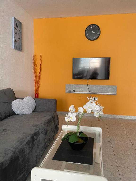 - un salon avec un canapé et une horloge murale dans l'établissement Apartament Monserrat, à Torrevieja