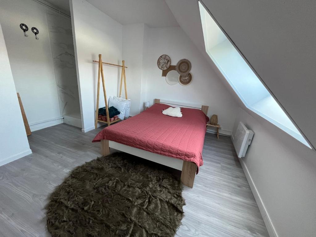 Habitación pequeña con cama roja y alfombra. en Appartement Calais Nord en Calais