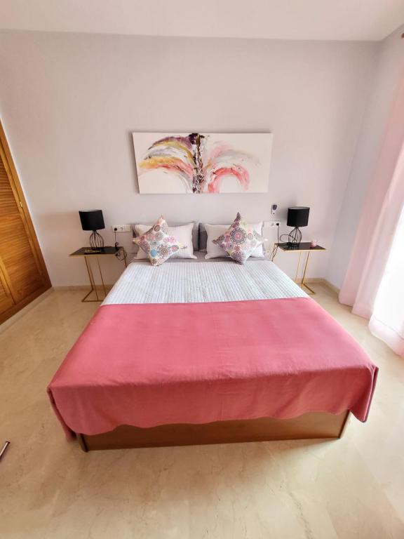 トレモリノスにあるAPARTAMENTO PLAYA LA VIÑA Pのベッドルーム1室(ピンクの毛布付きの大型ベッド1台付)