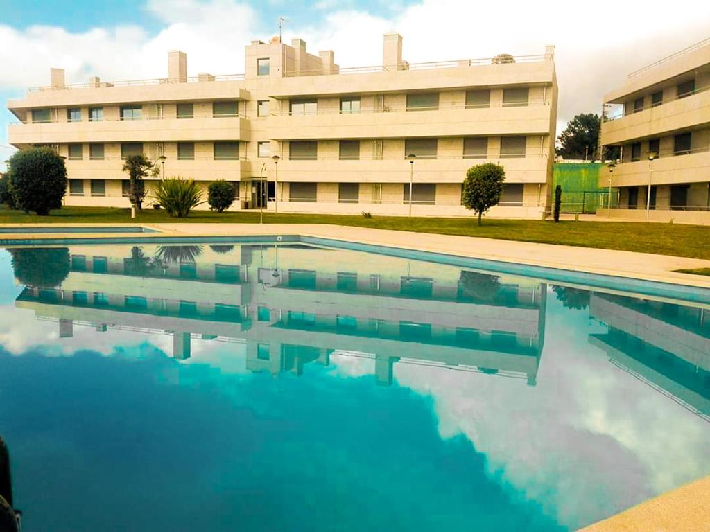 una gran piscina frente a un edificio en BEACH FRONT APARTMENT - with swimming pool, barbecue and tennis court!, en Viana do Castelo