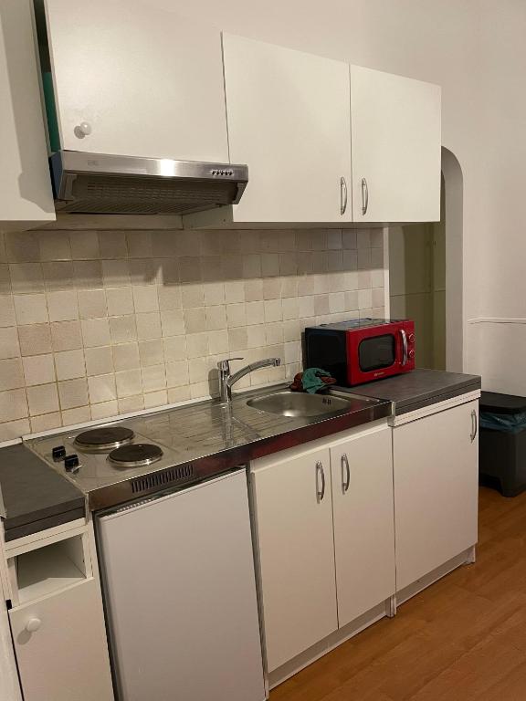 a kitchen with white cabinets and a sink and a microwave at Beau F2 Paris face gare de Rosny in Rosny-sous-Bois