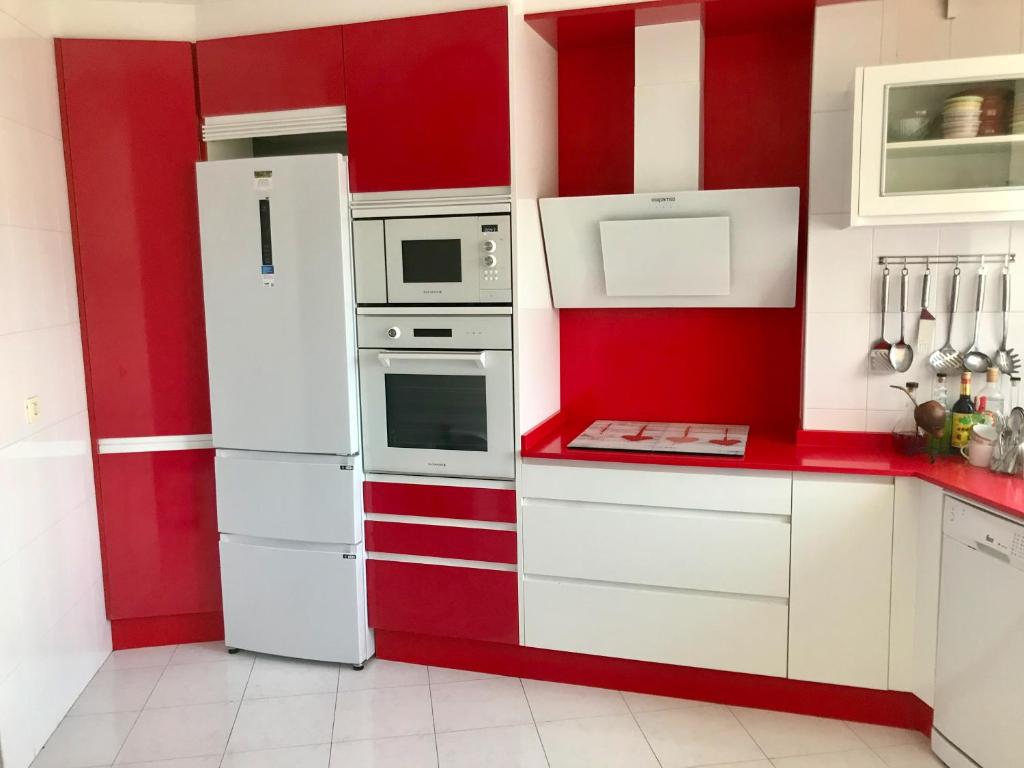 una cocina roja y blanca con electrodomésticos blancos en Apartamento As Lagoas, en Bueu