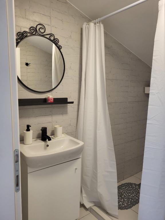 a white bathroom with a sink and a mirror at Apartment By the River in Niš